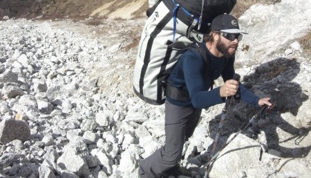CLIMBER CARRYING LARGE PACK UP A MOUNTAIN